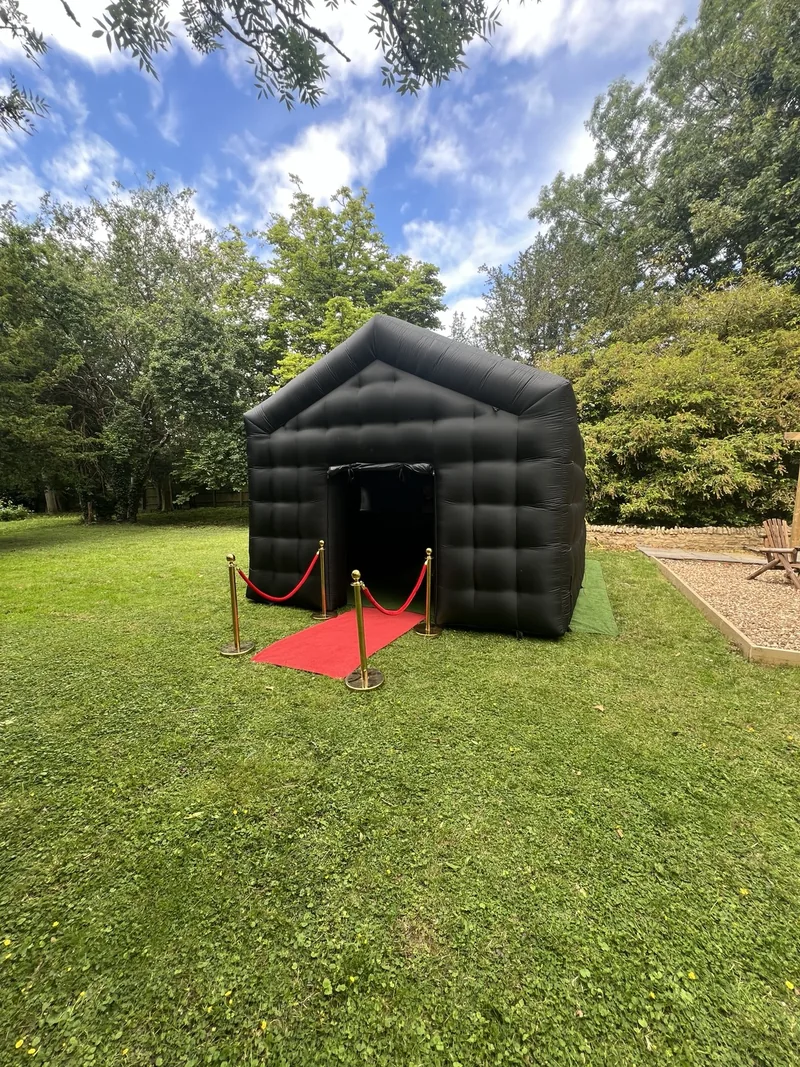 Ultimate black inflatable nightclub with a red carpet and gold VIP posts in a garden